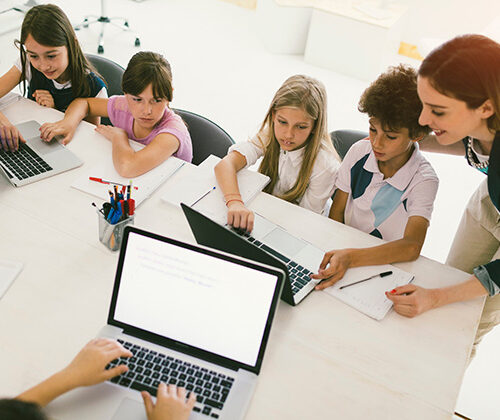Niños combinan tablets y cuadernos en clase, guiados por su maestra. Foto: MultiBriefs