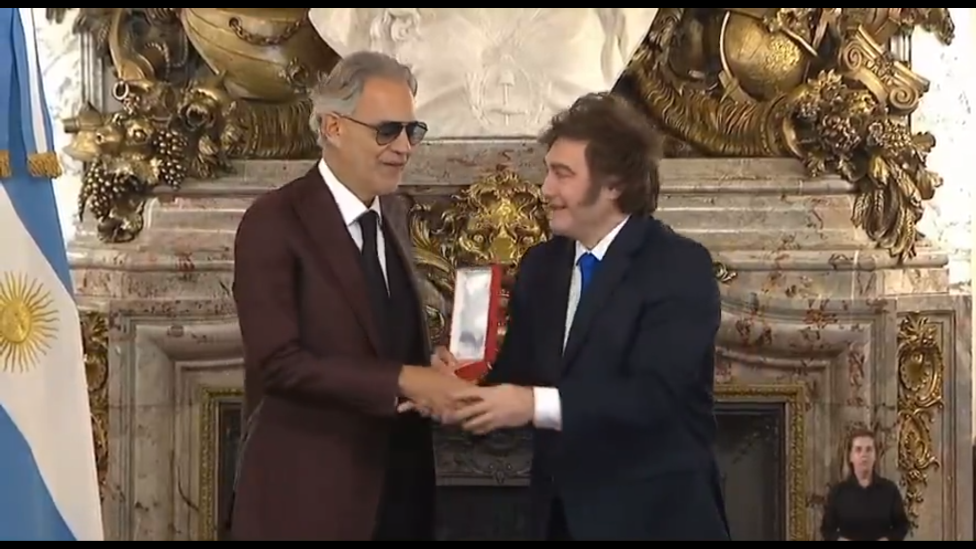 Javier Milei intenta saludar de mano a Andrea Bocelli tras condecorarlo, pero el tenor ciego no ve el gesto y genera risas virales en X. Foto: Cortesía.