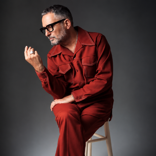 Retrato de un artista con traje rojo y gafas oscuras durante una sesión fotográfica en estudio. Foto: Cortesía.