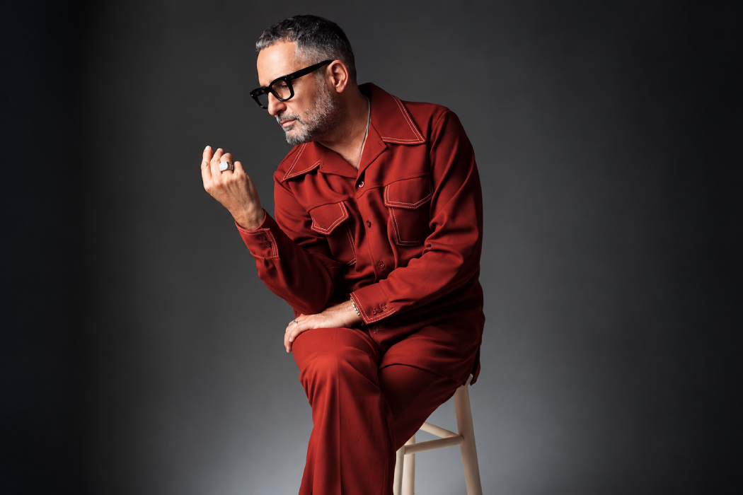 Retrato de un artista con traje rojo y gafas oscuras durante una sesión fotográfica en estudio. Foto: Cortesía.