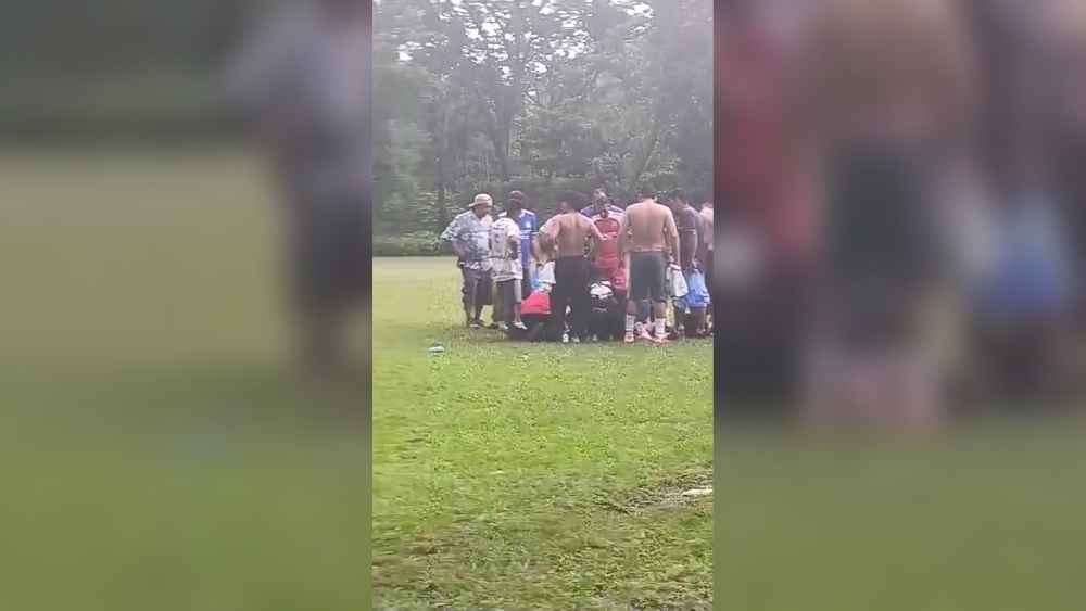 Varias personas permanecen en la cancha de fútbol de Izalco donde un rayo dejó seis afectados este domingo. Captura de video/redes sociales.