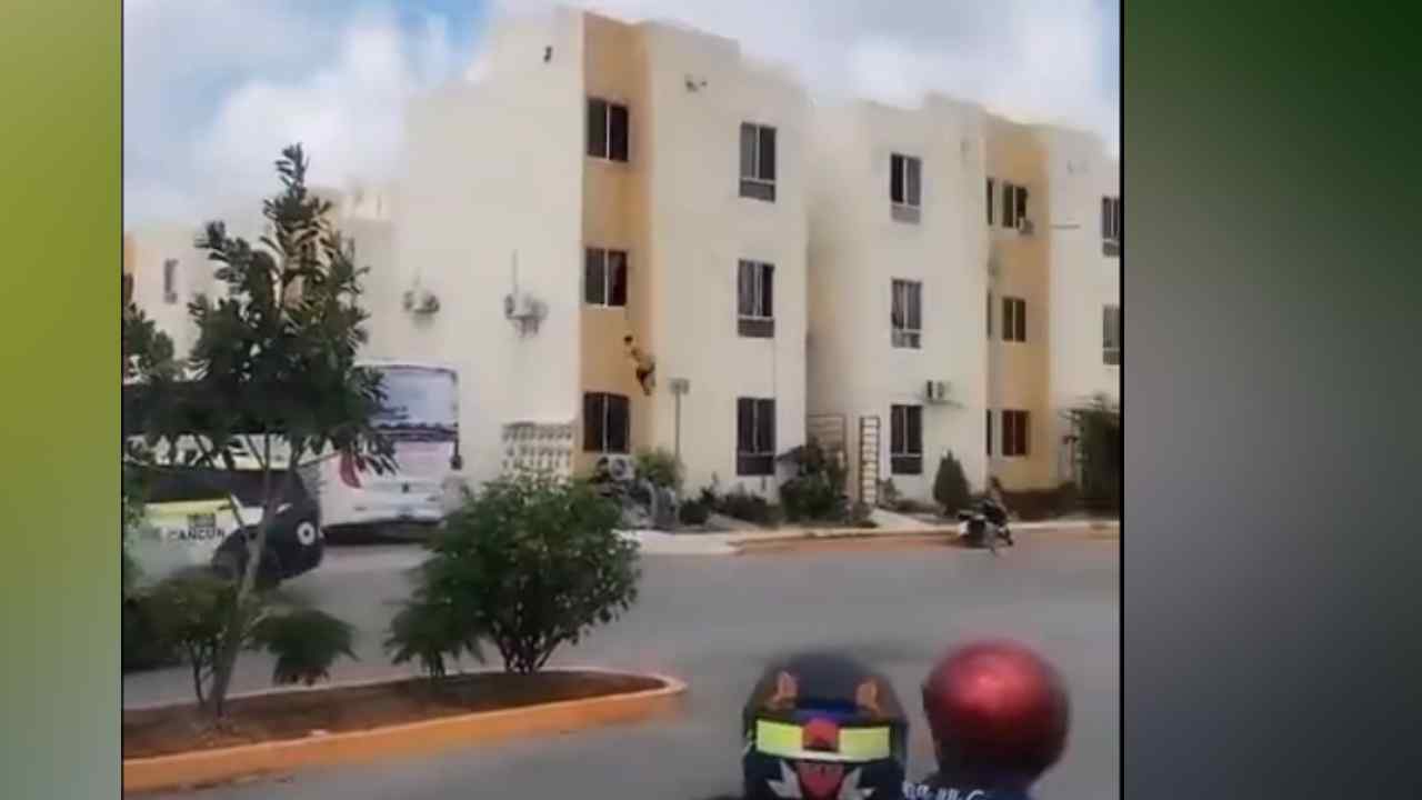 Un hombre semidesnudo quedó suspendido de una ventana en un edificio de Cancún antes de sufrir una aparatosa caída el 12 de octubre de 2026. Captura de pantalla