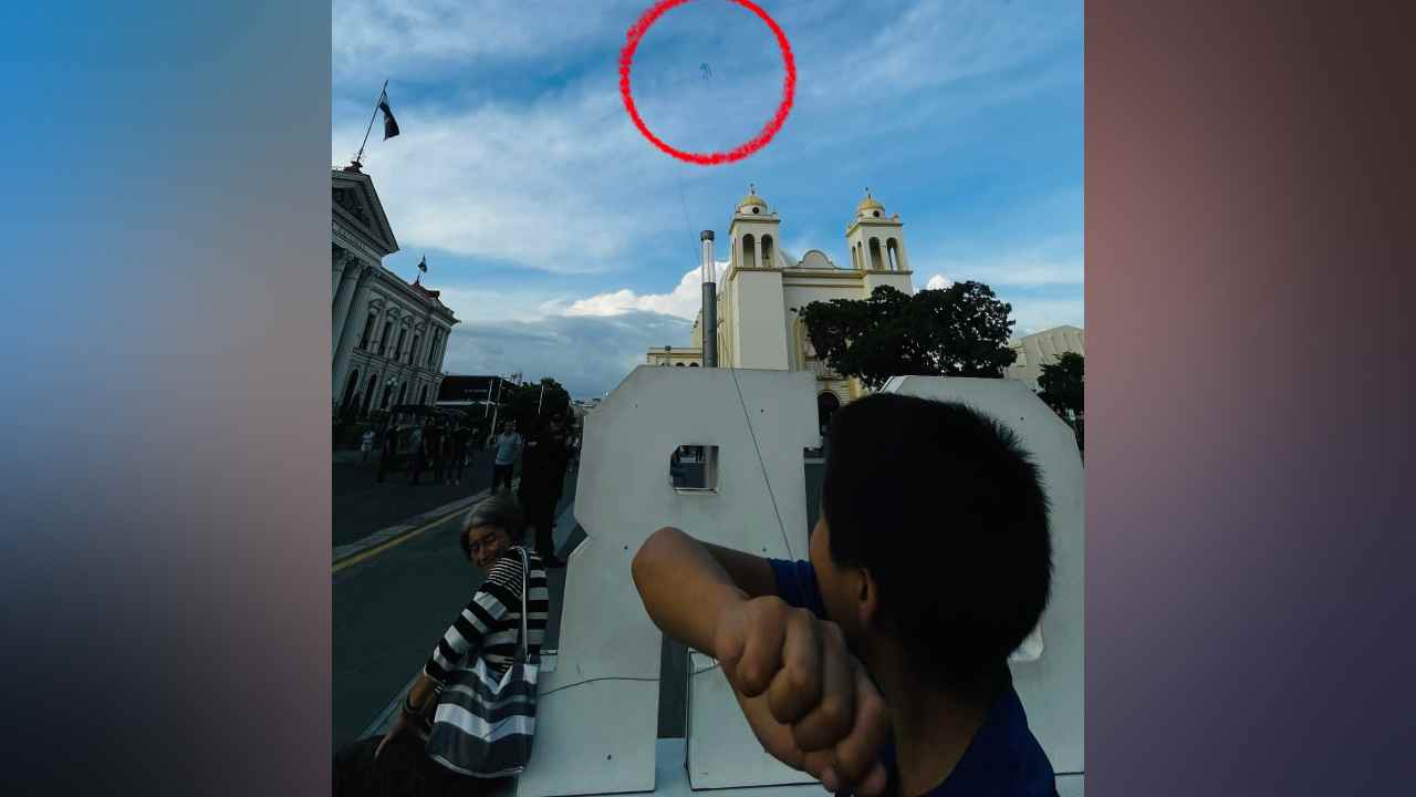 Nahúm Ezequiel eleva una piscucha en la plaza Gerardo Barrios, frente a la Catedral Metropolitana de San Salvador, acompañado de su abuela, Rosa Emilia. Una escena que mantiene viva una tradición de los octubres salvadoreños. Foto: Juan José López / Publimetro El Salvador
